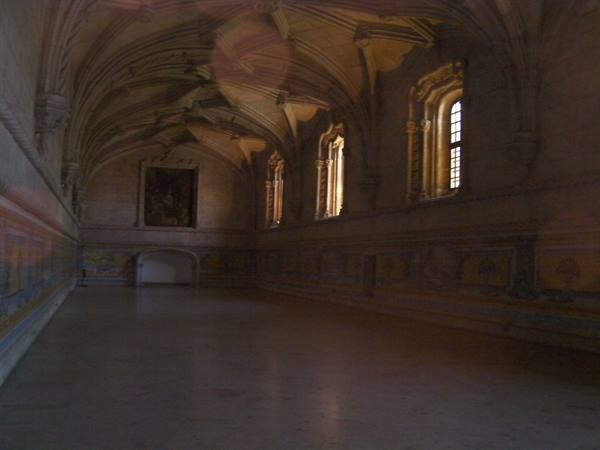 Vaulted stone hall with tiled walls, light streaming through gothic windows