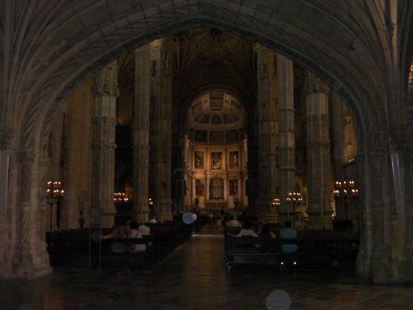 Gothic interior of Jerónimos Monastery church, carved twisted columns, visitors seated