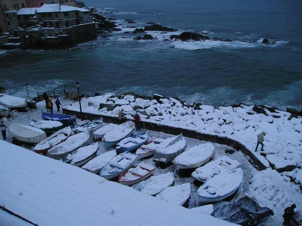 Snow-covered fishing boats in the small harbor of Boccadasse, Genoa