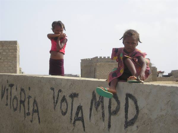 Children sitting on concrete wall with painted electoral writing