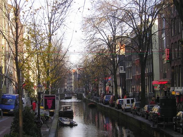 Boat on Amsterdam canal between brick houses and bare trees