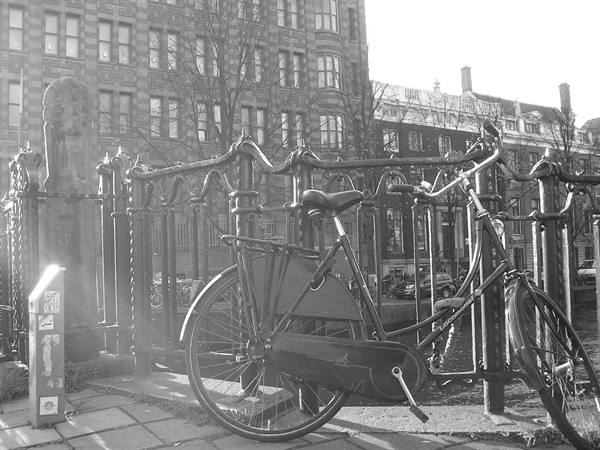 Bicycle chained to the wrought iron railing of an Amsterdam canal bridge