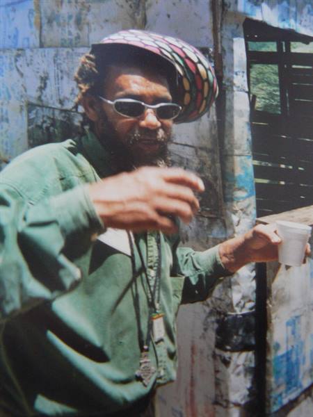 Rasta man in colorful hat and sunglasses holding a plastic cup