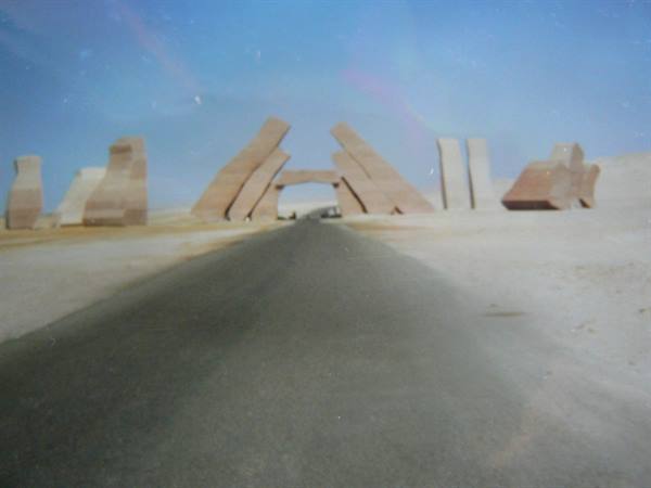 Paved road crosses tilted stone sculptures in the desert