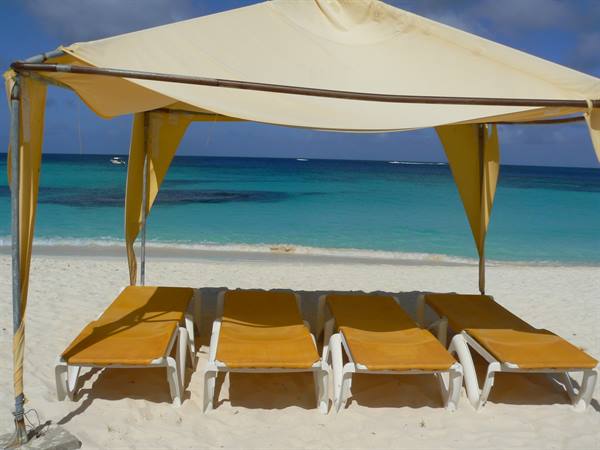 Yellow canvas canopy and four sun loungers on white sand, turquoise sea