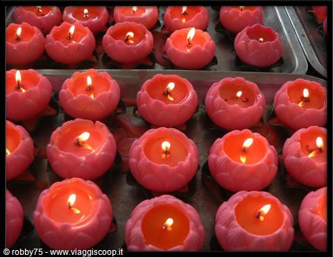 Red lotus-shaped candles burning, arranged on metal trays