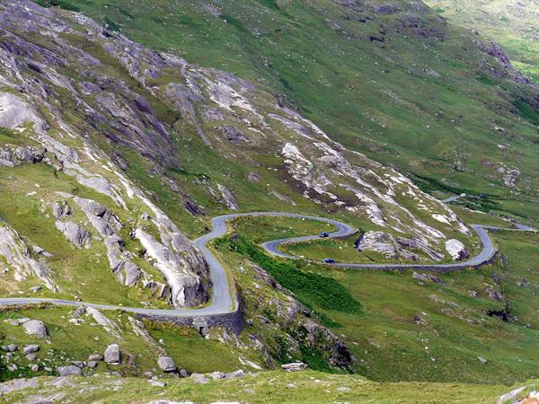 Winding road with stone walls through rocky green slopes, Healy Pass