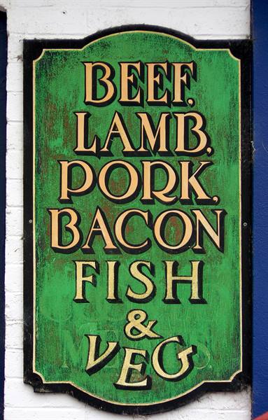 Vintage green sign with golden lettering: Beef, Lamb, Pork, Bacon, Fish & Veg