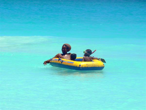 Woman and children on yellow inflatable boat in turquoise sea, child with snorkel mask