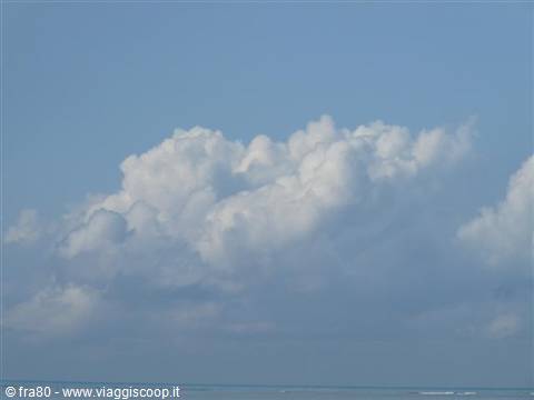 Fluffy white clouds above the blue sea on a clear day