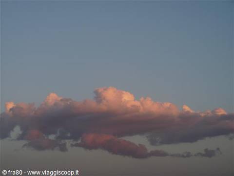 clouds glowing pink in fading light against a blue sky