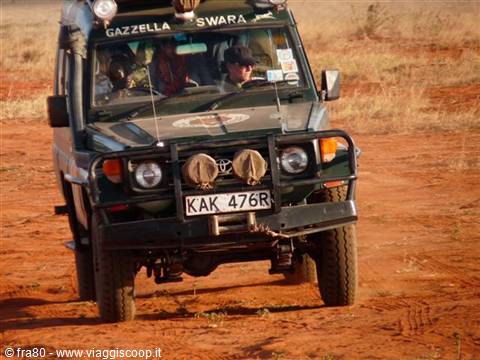 Toyota Land Cruiser safari driving on red dirt, driver in cap