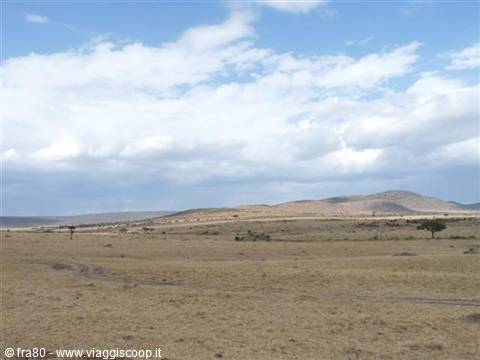Dry African savanna with brown hills under a sky full of white clouds