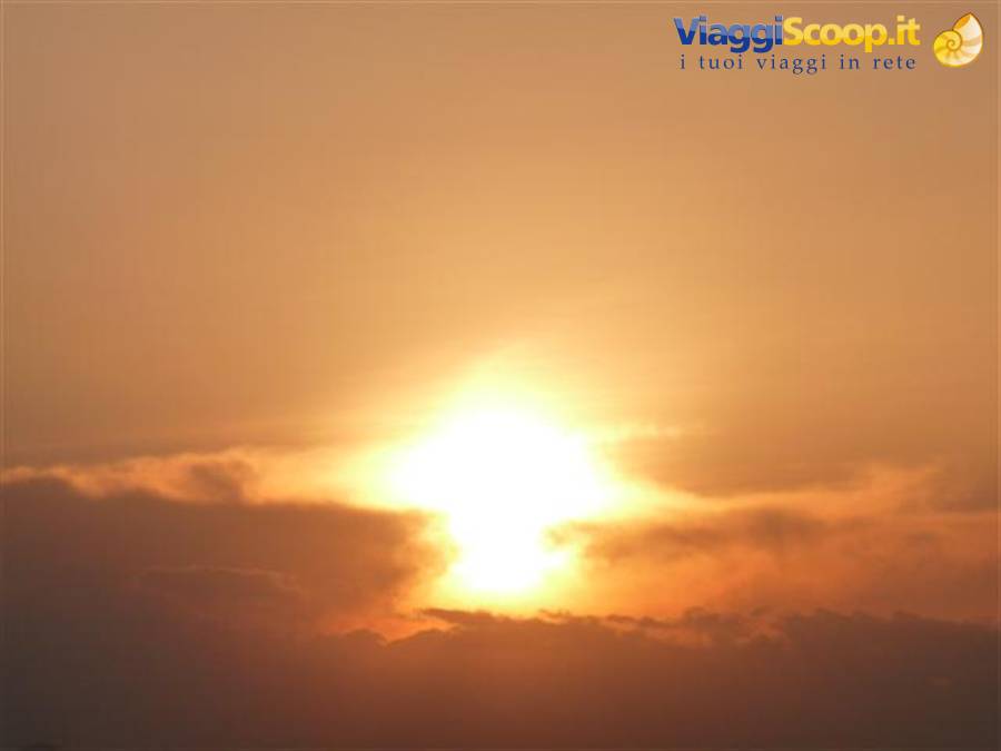 Bright sun glowing through orange clouds in hazy sky