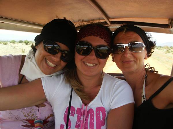Three smiling women wearing sunglasses inside a safari jeep under the canopy