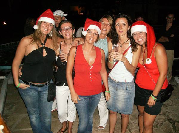 Friends wearing Santa hats toast together at night