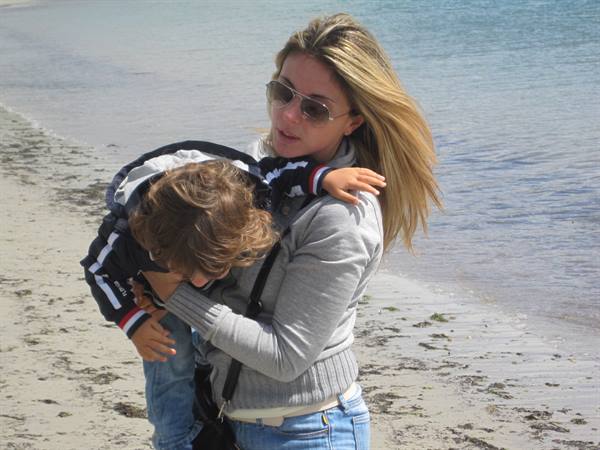Blonde woman with sunglasses holding a child on the beach