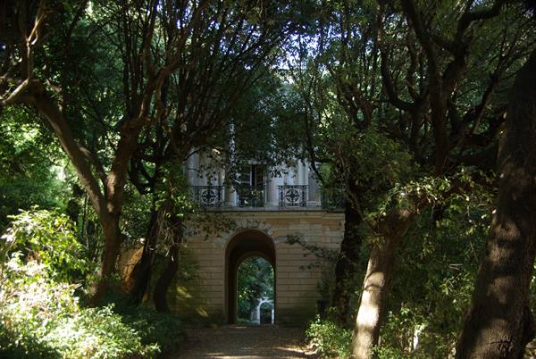 Neoclassical stone pavilion among old trees, shade and filtered light
