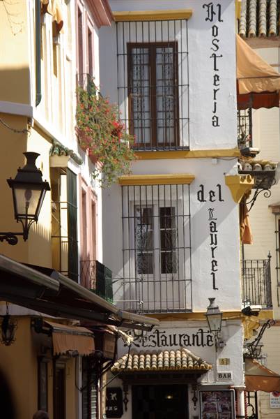 White and yellow facade of Hosteria del Laurel with iron grilles, lanterns and flowers