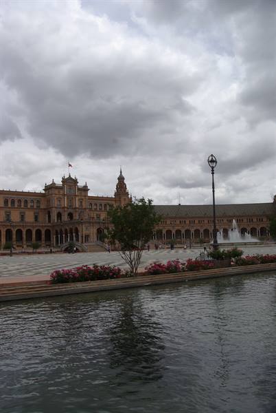 Plaza de España in Seville, fountain and flowerbeds under cloudy skies