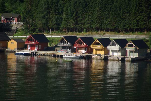 Colorful wooden boathouses on stilts line the dock, boat moored on calm water