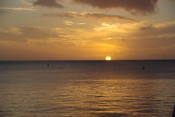 Low sun over golden ocean, floating buoys and glowing clouds