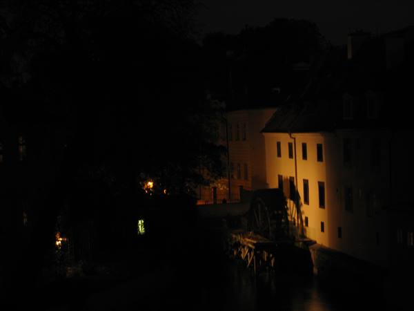 night canal, wooden waterwheel beside a warmly lit building