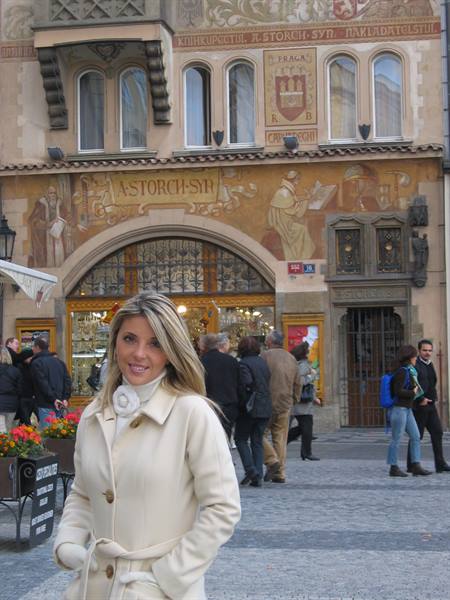 Blonde woman in cream coat in front of the Storch house in Prague