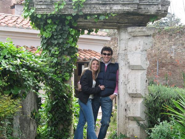 Smiling couple under an ancient travertine portal covered in ivy
