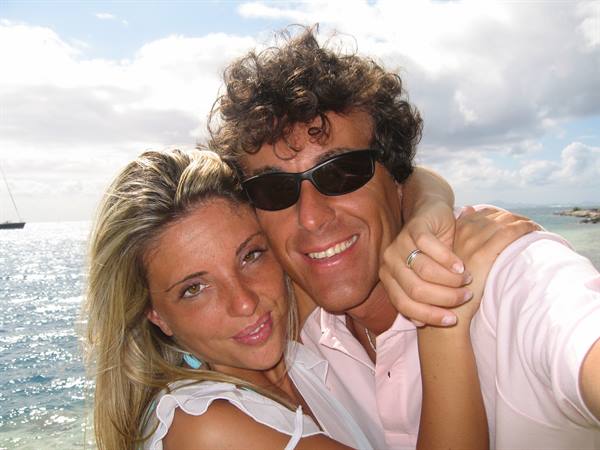 Smiling couple hugging by the sea, he wears sunglasses
