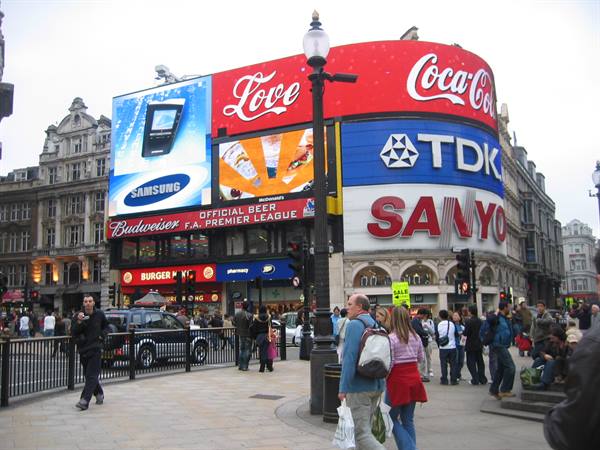 Crowd walking beneath illuminated Coca-Cola and TDK billboards at Piccadilly Circus