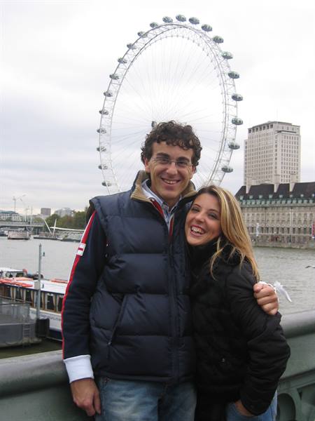 Couple smiling in front of the London Eye and the Thames
