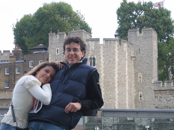 Couple embracing in front of a medieval stone fortress, soft daylight, British flag
