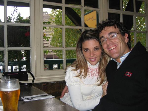 Smiling couple at a pub table with beer, natural window light