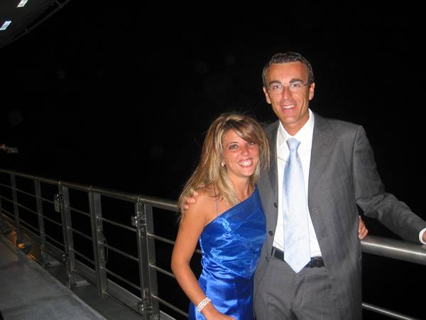Smiling couple in blue dress and gray suit on a ship deck at night