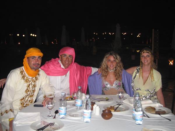 Four people in costumes celebrating at a themed dinner table at night