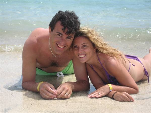 Smiling couple lying on wet sand in front of sea waves