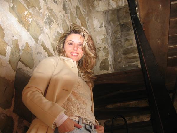 Smiling woman in beige coat on an old stone staircase