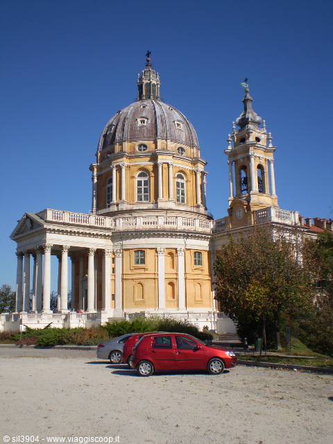 Basilica di Superga: grey dome and columned portico under blue sky, parked cars