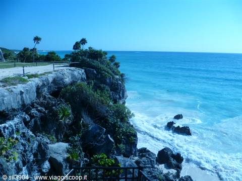 Limestone cliff over turquoise Caribbean sea with palms, Tulum coast