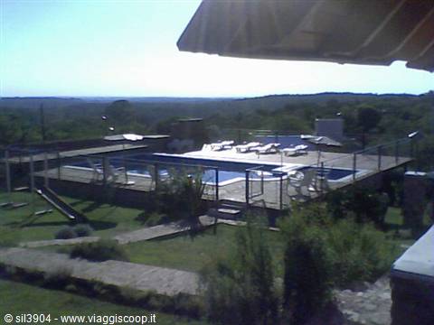 Outdoor pool with loungers and parasol, green hills under the sun