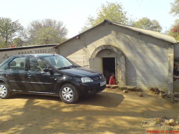 Black car parked in front of concrete house with arched doorway