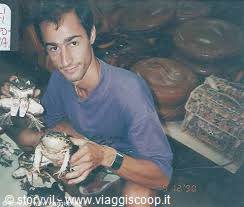Smiling man holds a stuffed frog at a souvenir stall