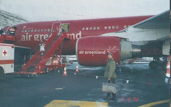 Traveler with bag next to a red Air Greenland plane on the ice