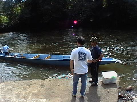 Tourist and guide beside a long blue boat on the river