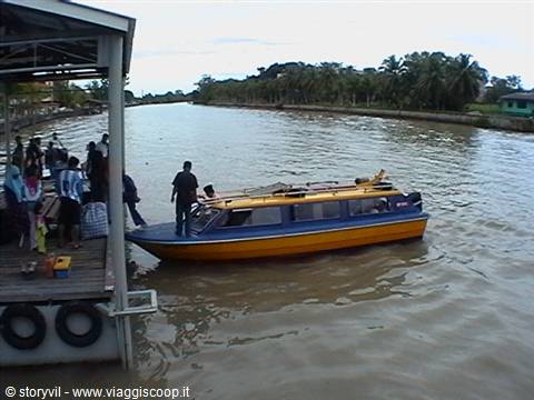 Yellow and blue water taxi moored at wooden jetty on muddy river
