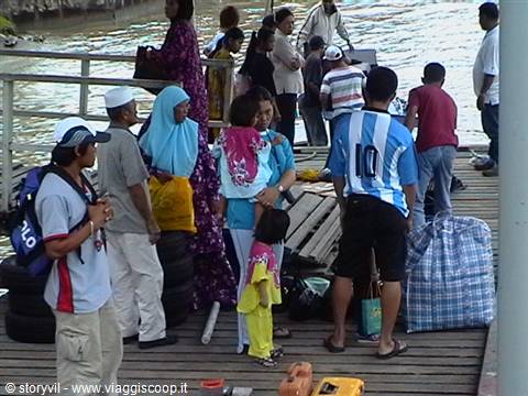 Travelers with luggage boarding a wooden boat, veiled woman among the crowd