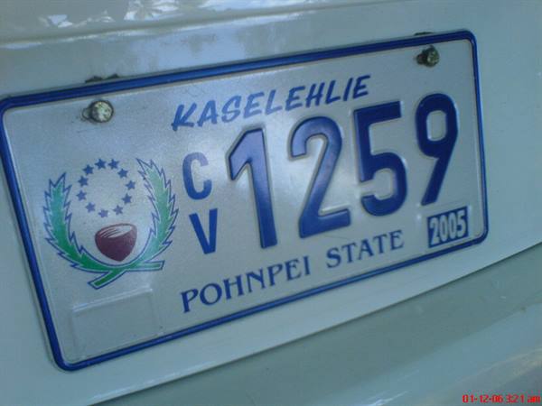 Blue and white Pohnpei State 2005 license plate with Kaselehlie emblem on car