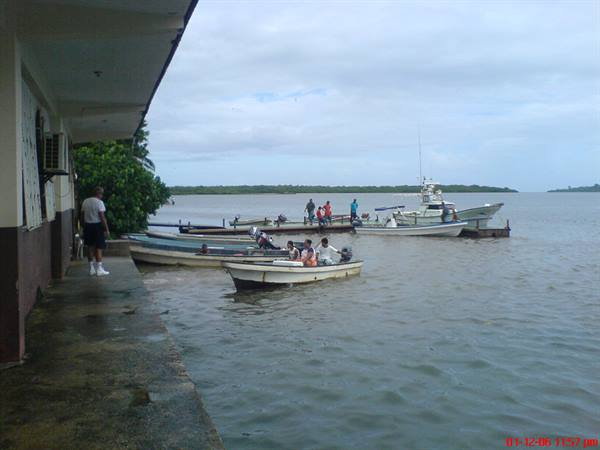 Fishing boats moored at the dock, people waiting under a cloudy sky