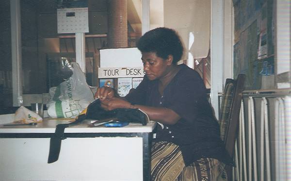 Woman at a tour desk works on an item inside her bag